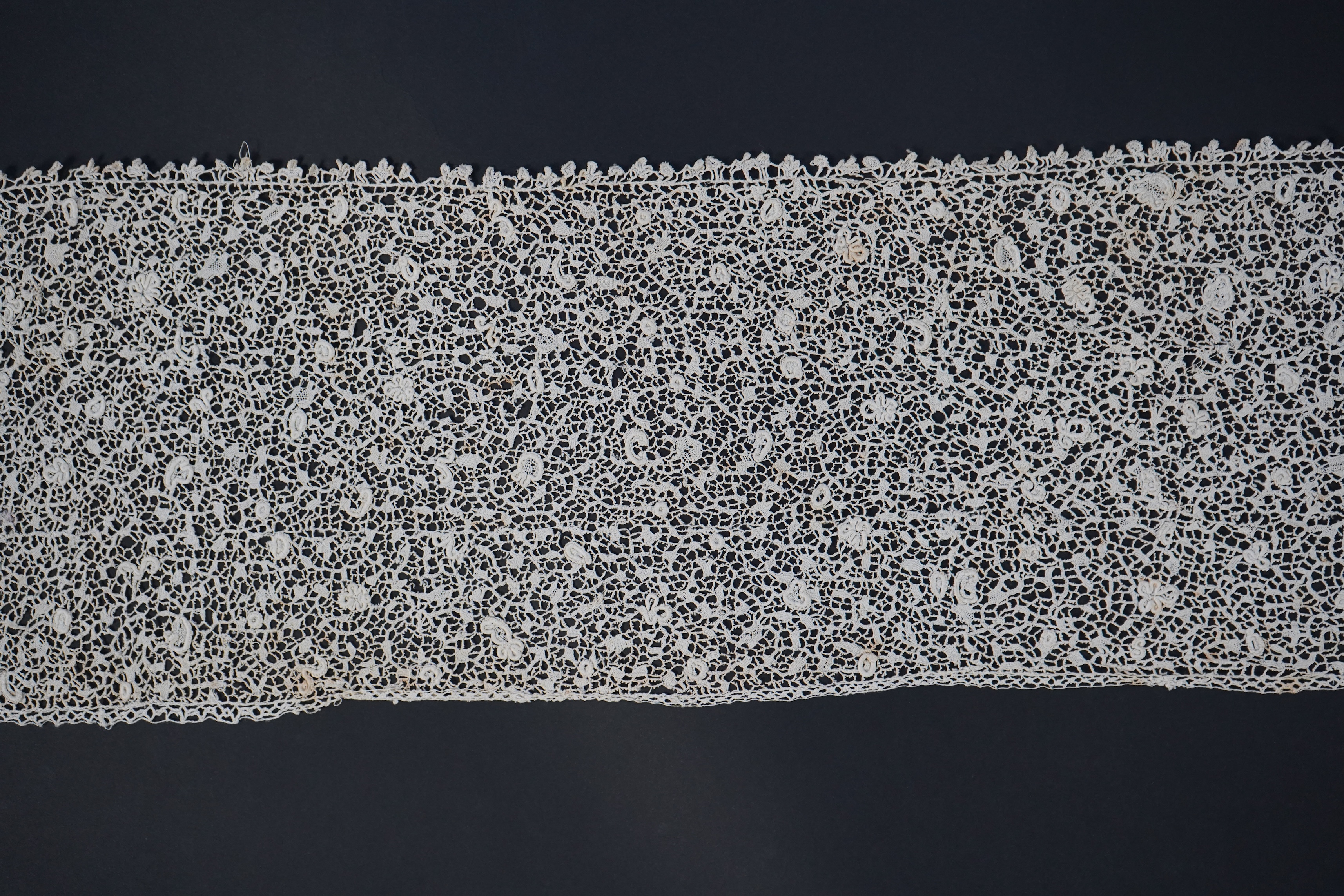 A late 17th century wide flounce of Point de France needle lace, together with a narrower flounce, both with raised elements of the design in the style of Point de Rose, but less so. This lace was very popular with the F